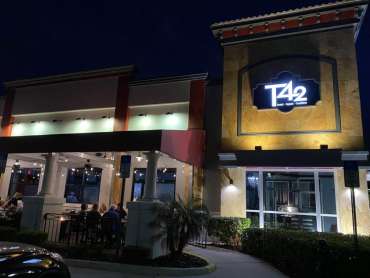 A group of people sitting at tables outside of a restaurant.
